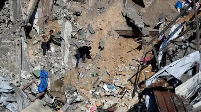 Two Palestinians seen among rubble in a top-down shot.