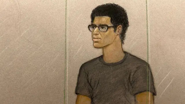 A court sketch of Nicholas Prosper sitting behind glass. He has black glasses on and has curly black hair. He is wearing a dark T-shirt.