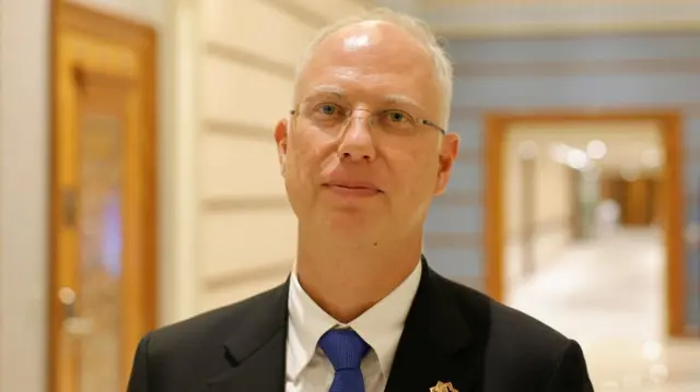 The head of Russia's sovereign wealth fund Kirill Dmitriev poses for a picture wearing a suit.