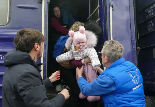 A man takes an infant off a train in Donetsk
