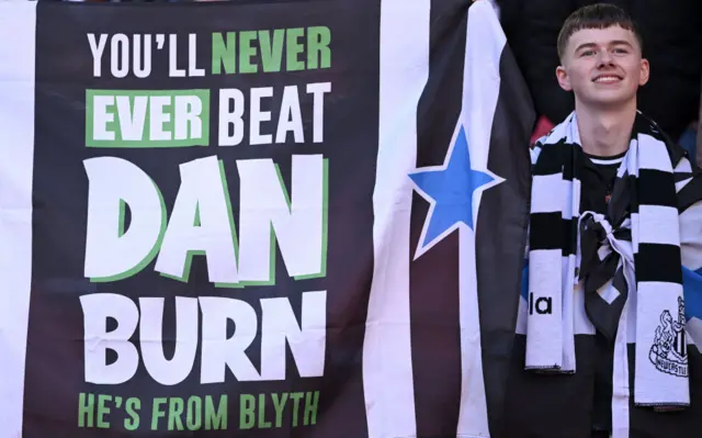 A Newcastle fan holds up a Dan Burn flag