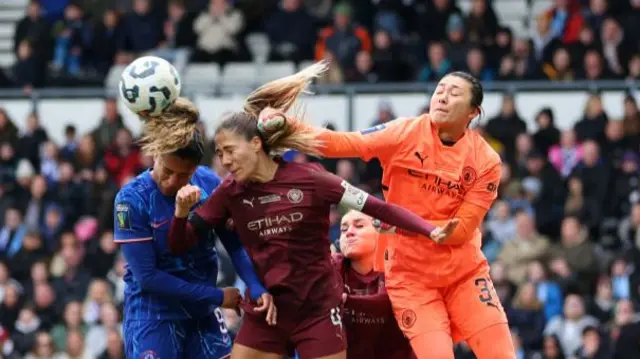 Yamashita tries to punch the ball clear as Aleixandri and Macario try to head it