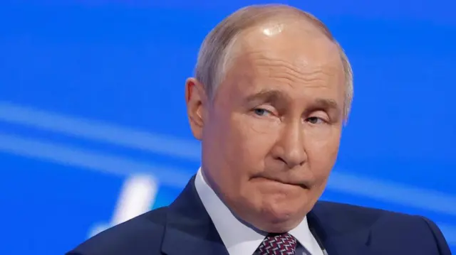 Putin looks to the side wearing a suit.