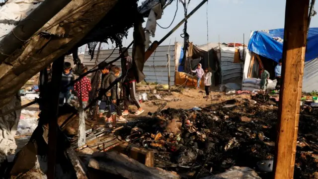 Palestinians inspect the site of an Israeli strike on a tent camp housing displaced people, in Al-Mawasi area, in Khan Younis in the southern Gaza Strip