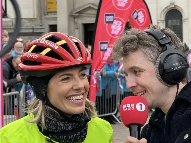 Mollie King smiling with Matt Edmondson holding a microphone, at the finish line of her challenge for Comic Relief last year