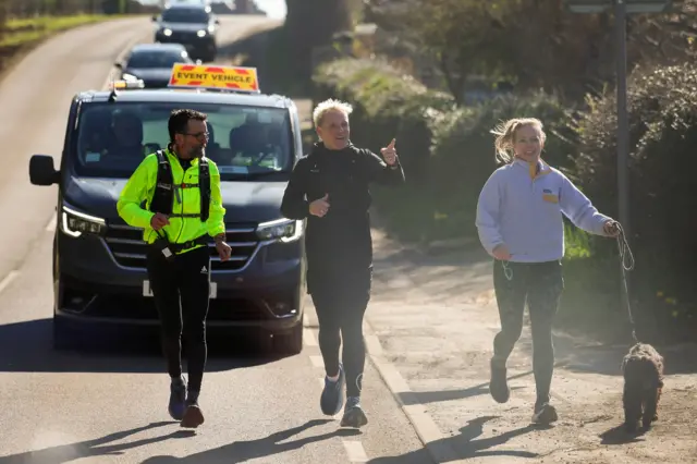Jamie Laing running alongside a jogger and a dog