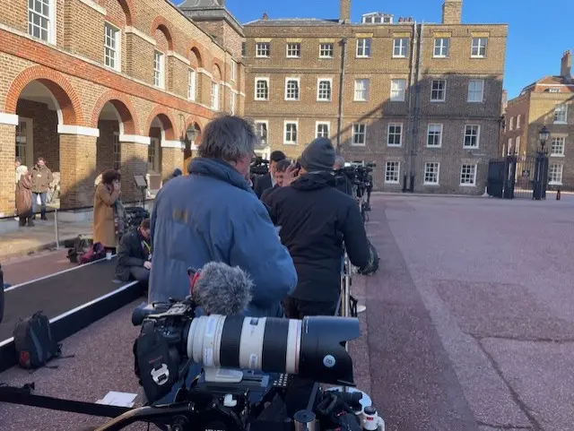 Camera queue stood in a line outside a historic building.