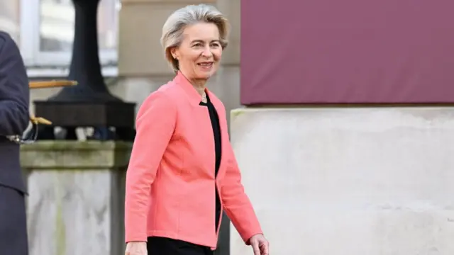 Ursula von der Leyen in pink blazer, walking.