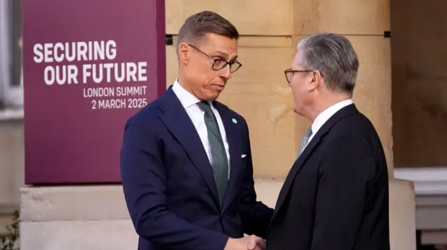 Alexander Stubb (L) shakes hands with Keir Starmer (R) as he arrives to Lancaster House in London for the leader's summit