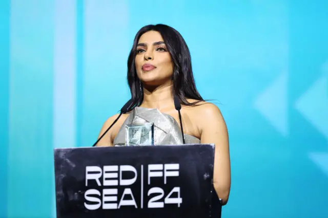 Priyanka Chopra Jonas on stage at the Yusr Awards Ceremony wearing a silver dress