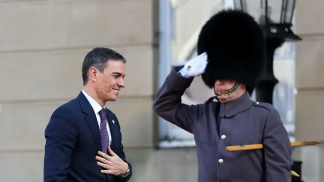 Spanish Prime Minister Pedro Sanchez walks past a guard making a salute