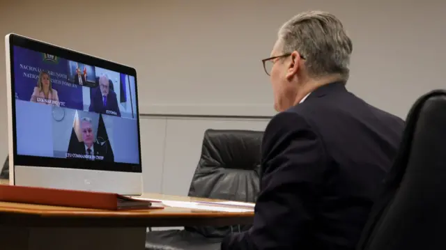 Sir Keir Starmer sitting down at a desk while speaking to three Baltic leaders via video call. He's sitting on a black leather chair wearing a black suit