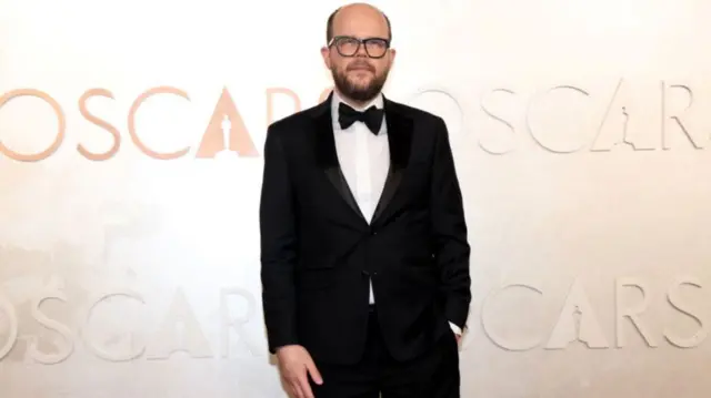 Nick Emerson poses during the Oscars arrivals wearing a classic Black tuxedo