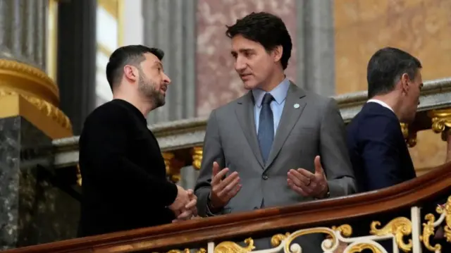 Zelensky looks up towards Trudeau mid conversation as the pair stand on the stairs