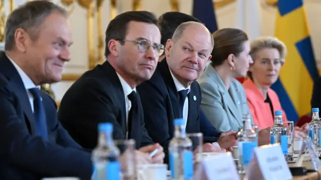 Olaf Schloz sits at the centre - the leaders seated around him are slightly blurred