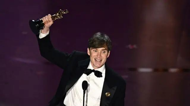 Cillian Murphy holding his Oscar trophy to the sky during his award's speech