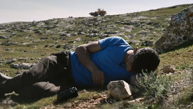 A man lying on a rocky hillside