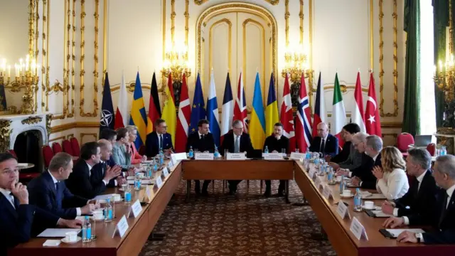 European leaders gathered around the summit table at Lancaster House. At the centre of the wooden table are Emmanuel Macron (L), Keir Starmer (C) and Volodymyr Zelensky (R)