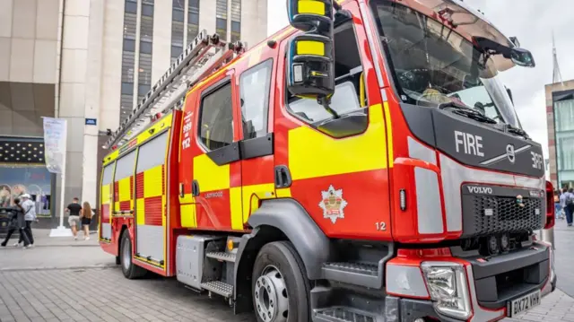 A red fire engine parked in a city centre street