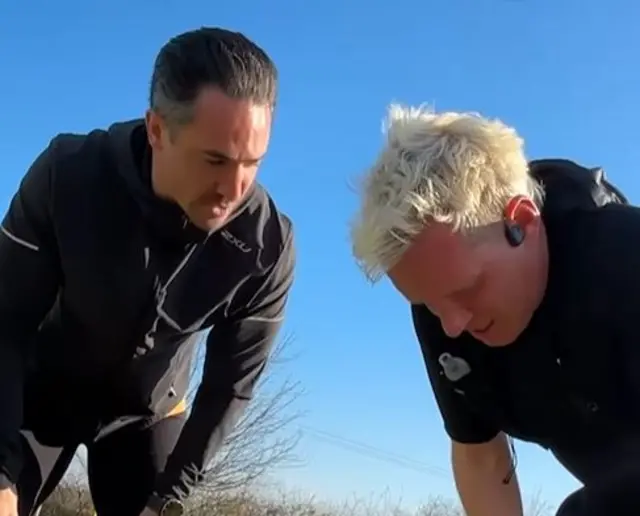 Jamie's friend JP speaks to Jamie as they're both bent over with their hands on their knees.