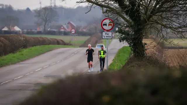 Jamie and his trainer running down an empty road in the countryside