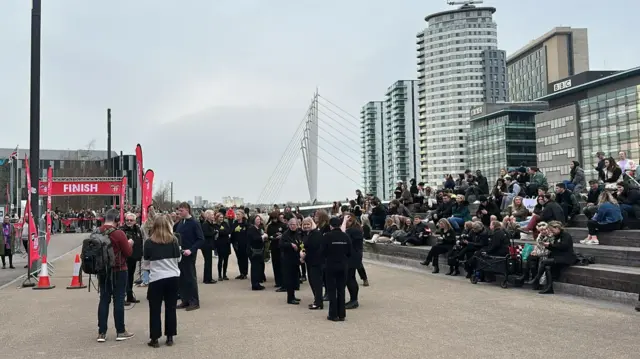 A crowd gathers at the finish line in Salford