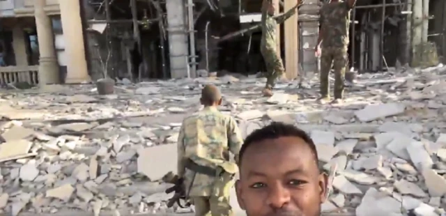 Soldiers in mobile footage outside palace with rubble on ground