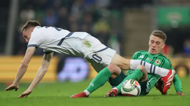 Michel Aebischer takes a tumble after this challenge from NI midfielder Ethan Galbraith