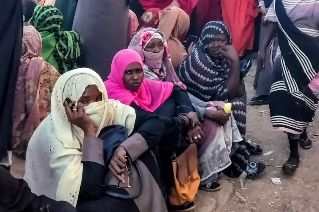 Sudanese women sit down as they wait at a local food kitchen