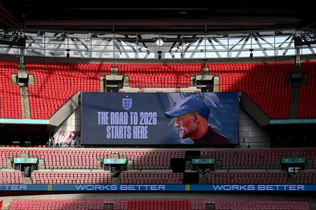 The LED screen displays a picture of Thomas Tuchel and a message reading "The road to 2026 starts here"