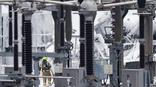 A firefighter douses flames of a fire that broke out at a substation supplying power to Heathrow Airport in Hayes, west London on March 21, 2025.