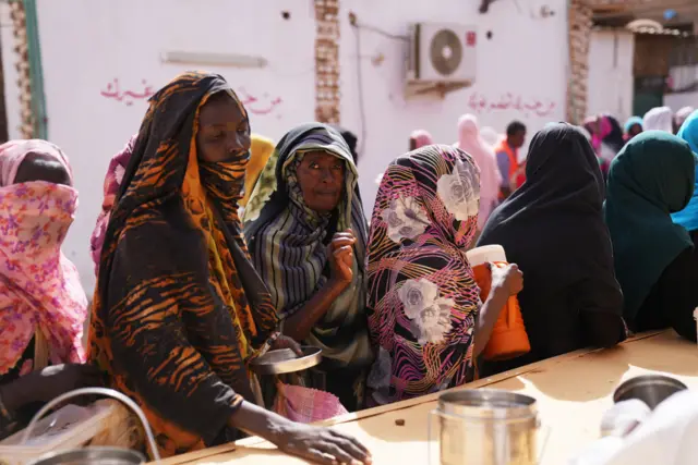 Woman stand in line at a community kitchen in Sudan