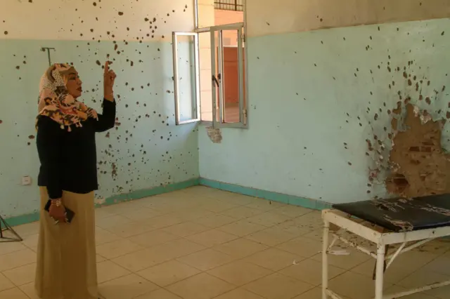 A doctir points to the ceiling where bombs and shrapnel have hit the hospital.