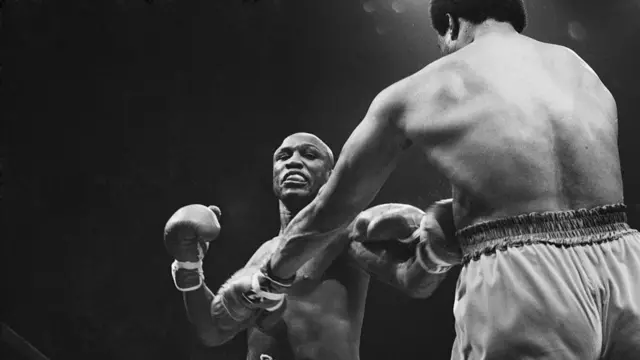 George Foreman punches Joe Frazier. The image is in black and white