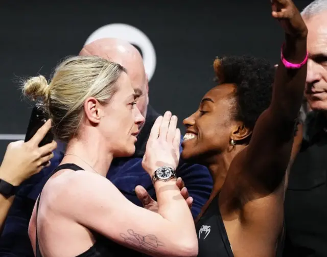 Molly McCann waves her hand in front of the face of Alexia Thainara at a UFC weigh-in