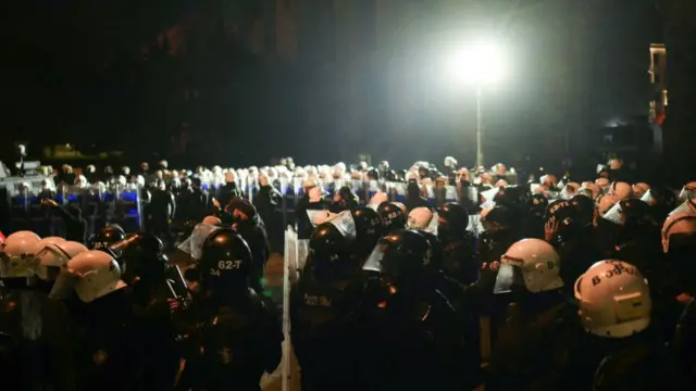 Riot police stand in a circle