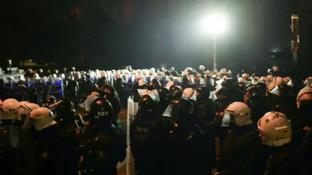 Large contingent of Turkish riot police wait on a dark street illuminated by only one light during protests in Istanbul