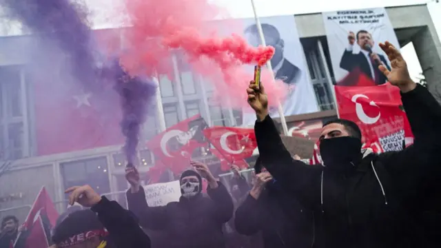 Protestors hold red and purple smoke flares during a rally in support of Istanbul's arrested mayor at Istanbul's city hall,