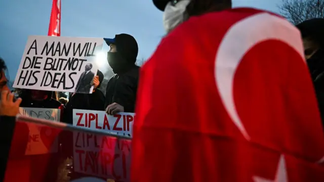 A protestor holds a sign reading "A man will die but not his ideas" with a picture of Turkish modern state's founding father Mustafa Kemal Ataturk