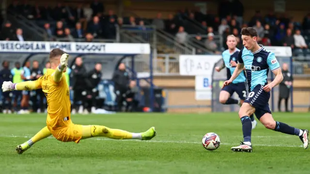 Cameron Humphreys of Wycombe Wanderers rounds George Wickens of Lincoln City to score the opening goal
