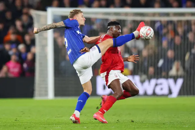 Taiwo Awoniyi of Nottingham Forest is challenged by Luke Woolfenden of Ipswich Town.