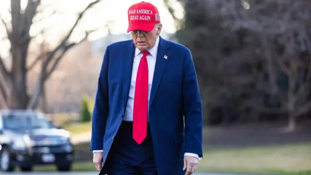 Donald Trump walks away from the White House wearing a blue suit and a red Make America Great Again hat