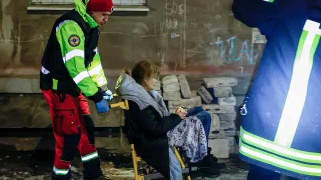 Rescue worker helps a local resident  on wheelchair exit residential building