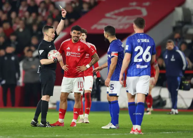 Referee Tony Harrington shows a yellow card to Sam Morsy