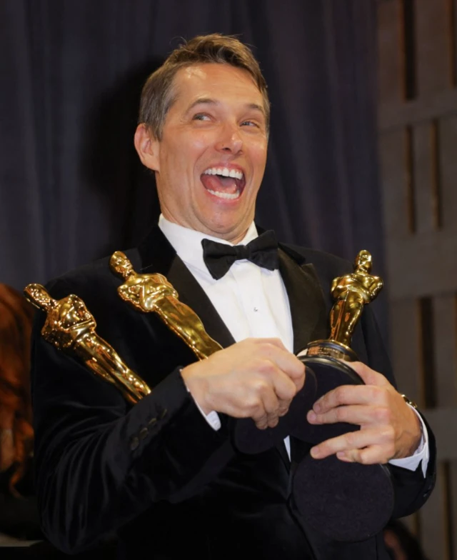 Sean Baker beams as he holds four Oscars