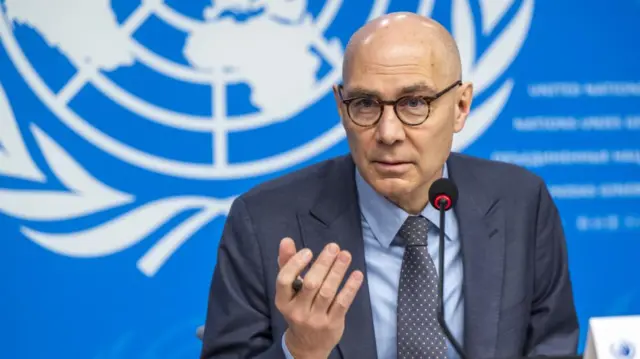 Volker Türk at a UN conference wearing a grey blazer and polka dot tie