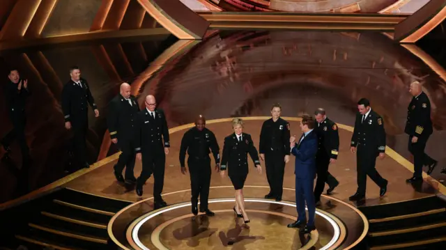 Show host Conan O'Brien welcomes firefighters to the stage during a tribute at the Oscars