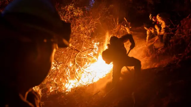 A large fireball is seen behind a soldier at nighttime