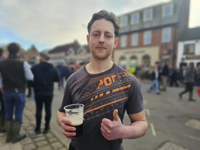 A man in a shirt with a beer in a plastic cup