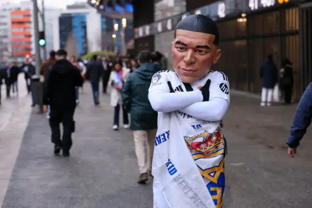 Real Madrid fan wears a Kylian Mbappe mask outside the Bernabeu